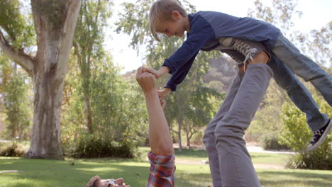 father and son playing on the grass in a park