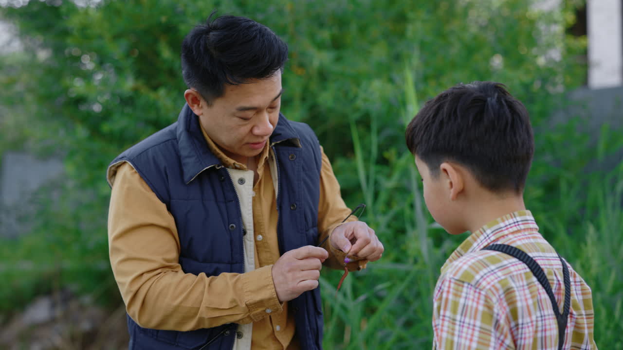 Father teaching his son how to prepare a fishing rod