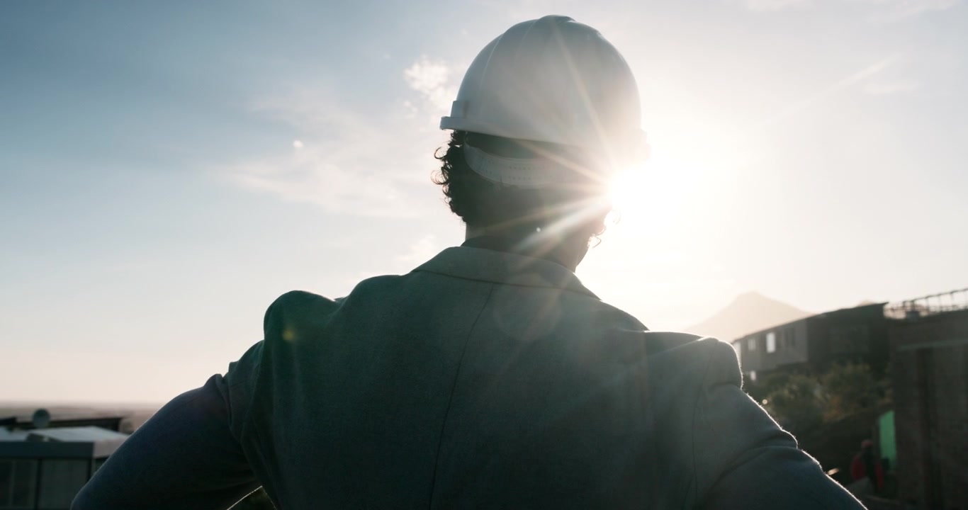 Architect Wearing Hard Hat Looking at Construction Site at Sunset