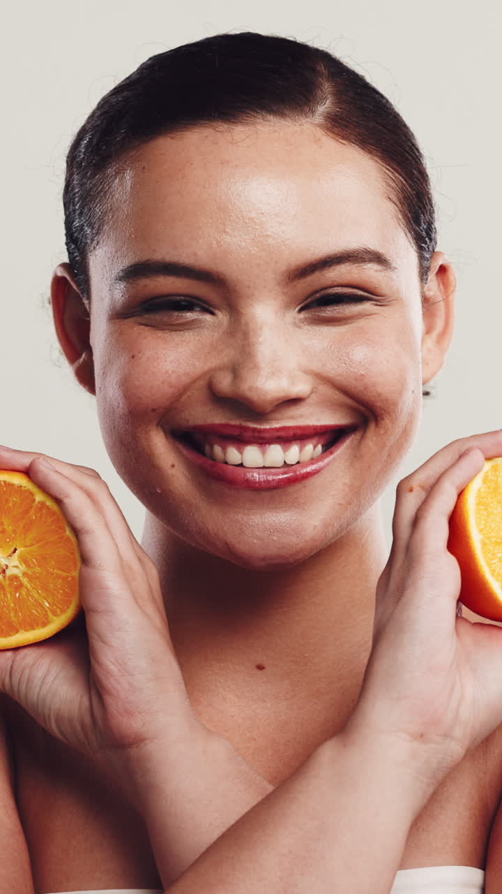 Mujer joven sonriendo y sujetando mitades de naranja fresca