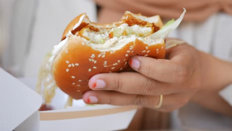 close-up of a woman's hand holding a burger