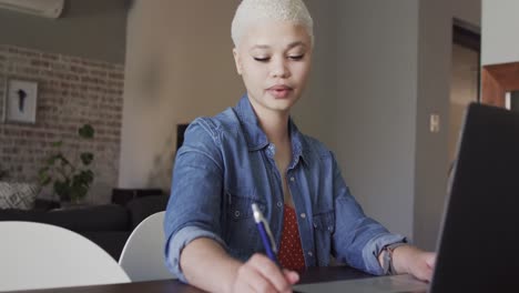 busy biracial woman working at home with laptop in slow motion