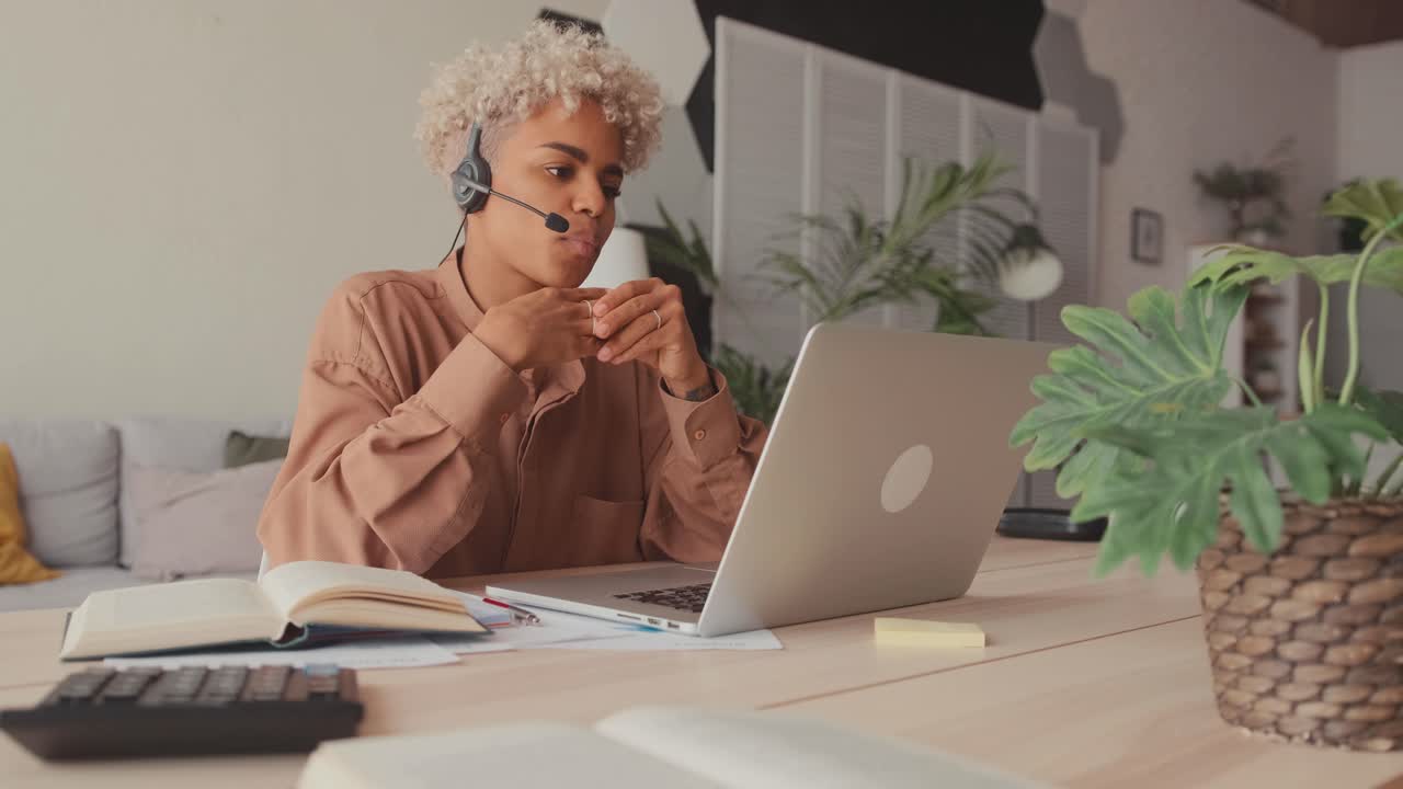 African female student wearing headset looking at laptop watching online webinar