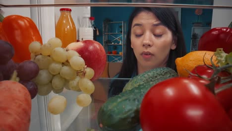 woman looking inside fridge, confused by food