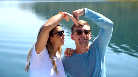 young pair sitting on bow of boat and posing into camera on sunny day. happy couple in love spending time together on deck of ship and enjoying summer travel. concept of vacation or holiday. close up front view