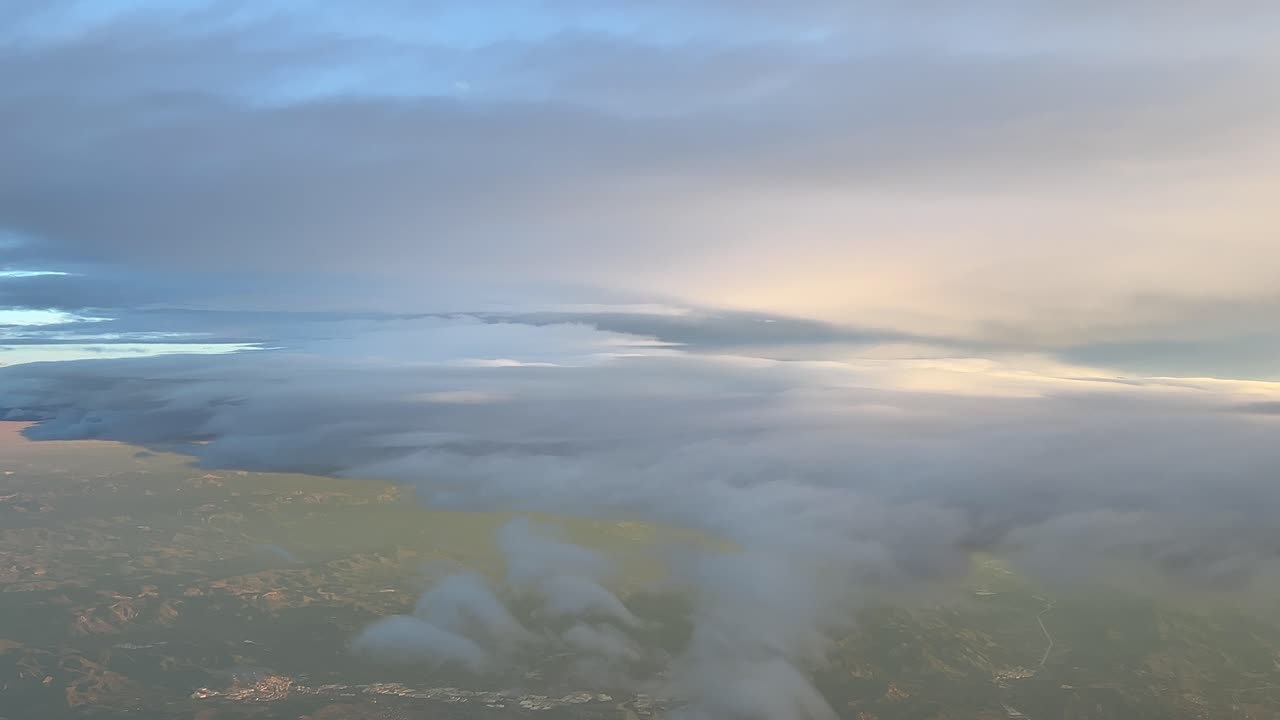 volando a través de un cielo colorido con algunas nubes mullidas temprano en la mañana cerca de la costa de barcelona, españa