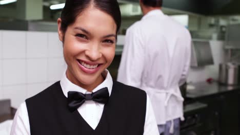 smiling waitress being handed a dish by chef