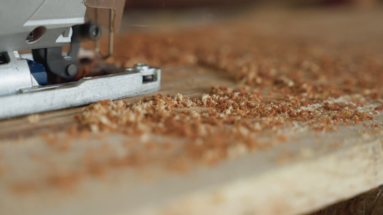 Closeup jigsaw cutting wood plank in dusty carpentry workshop, sawdust piling along metal base, blade trimming plywood edge, focus on wood shavings and grain texture, ideal for carpenter, furniture