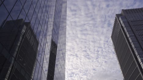 Vista-Tranquila-Y-Relajante-De-Los-Rascacielos-Que-Reflejan-Un-Hermoso-Cielo-Nublado-En-Cámara-Lenta