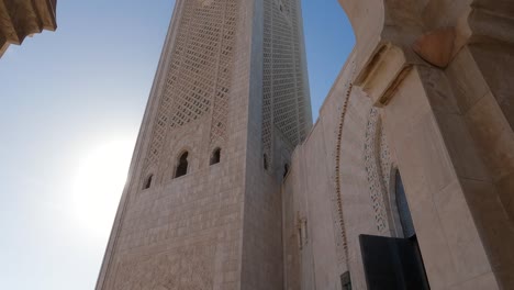 Colorful-Moroccan-tiles-on-wall,-view-tilt-up-onto-grand-Hassan-Mosque