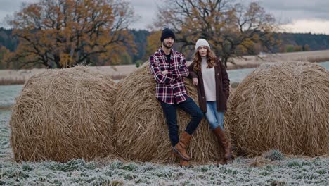 couple posing amongst hay bales on a frosty autumn day
