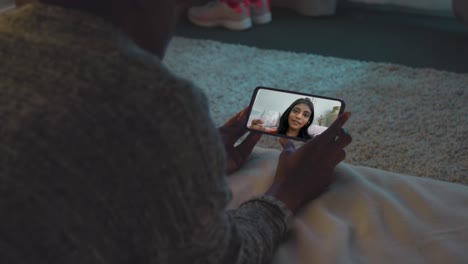 close up of woman lying on bed at home having video call with female friend drinking wine on mobile phone