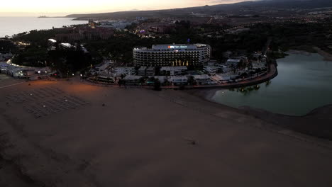 Dunes-of-Maspalomas,-Gran-Canaria:-aerial-view-in-orbit-over-the-lagoon-found-in-this-natural-area-and-during-the-golden-hour