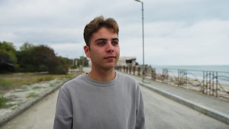 boy with a slight smile near the ocean on a cloudy day outdoor