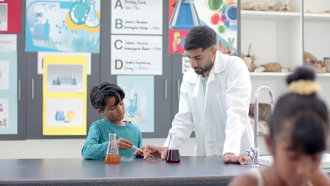 a young caucasian teacher helps a child in a white lab coat