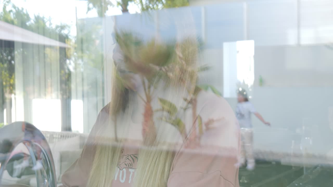 Woman looking through a window with a child in the background
