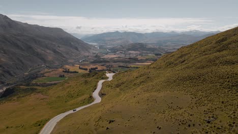 Antena-Sobre-El-Paso-De-Montaña-Cardrona-Con-Una-Carretera-Escénica-Que-Serpentea-Por-El-Valle