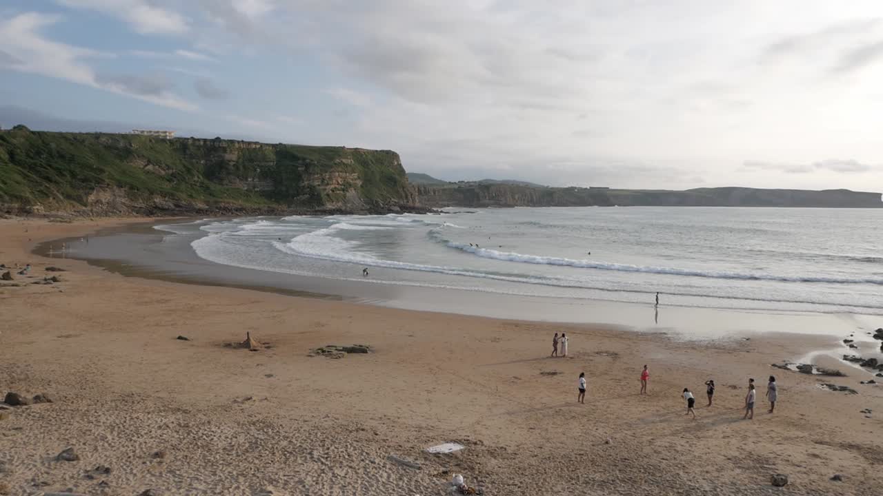 la gente disfruta de un día fresco en la playa de los locos en españa con las olas del mar