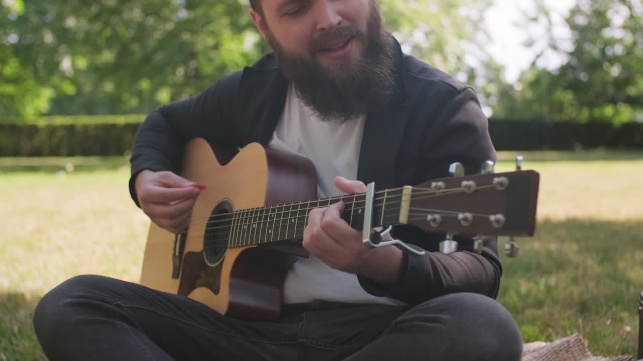 Man Playing Guitar in Park on Sunny Day