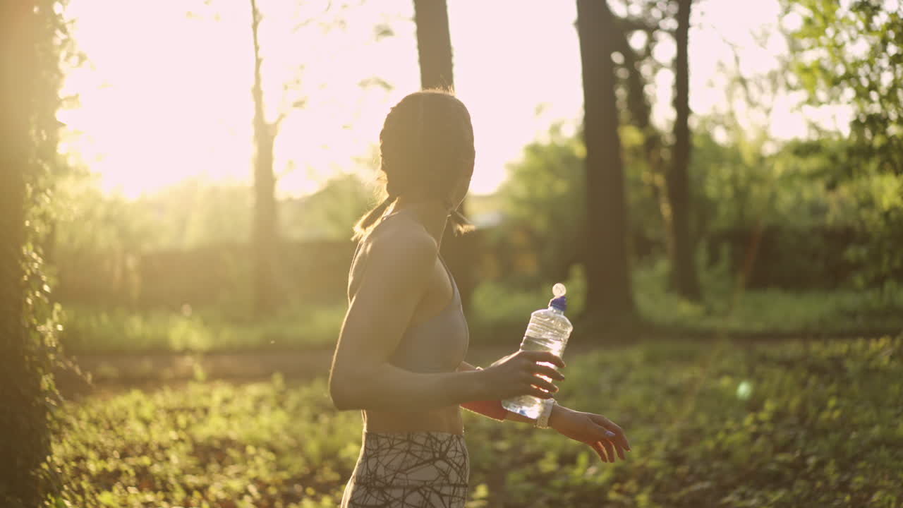 mujer bebiendo agua después de hacer ejercicio en el parque
