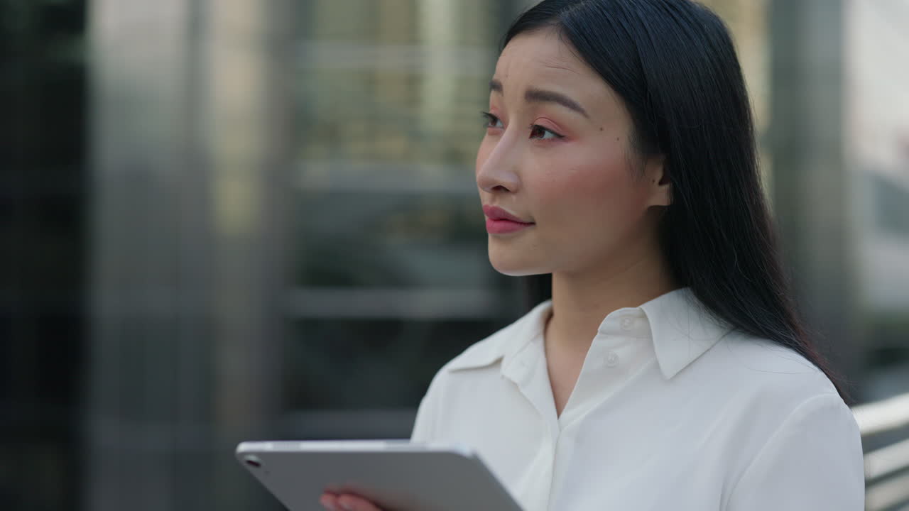 Young Asian businesswoman using a tablet outdoors in an urban setting