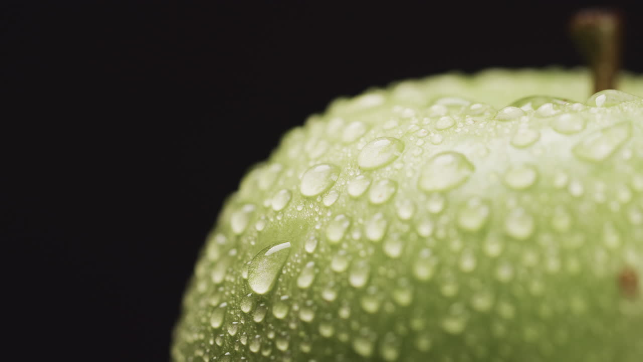 Primo piano di goccioline d'acqua sulla superficie di una mela verde, con spazio per il testo