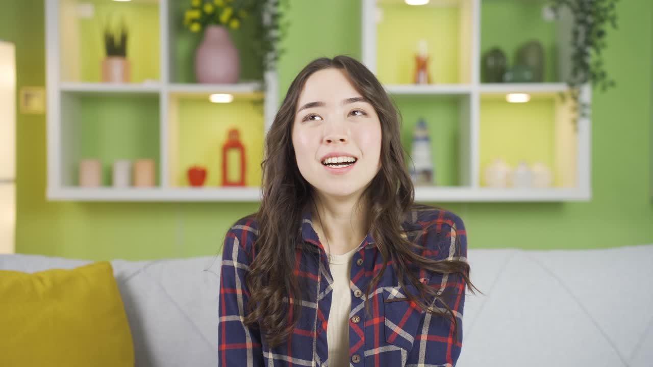 미소 짓는 아시아 젊은 여성이 카메라를 향해 손을 흔들고 있습니다.