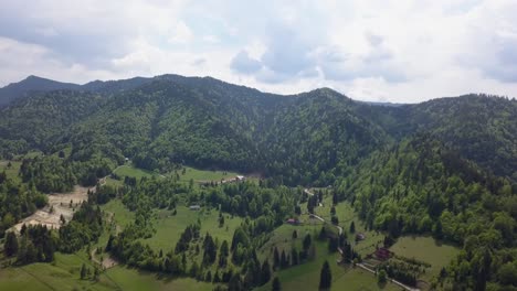 aerial panning of landscape valley with green woodland and partial cloudly skies