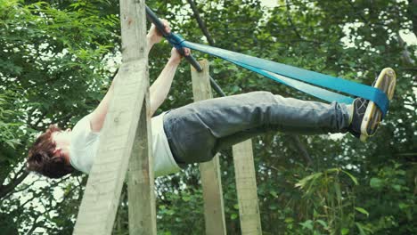 Young-man-performing-front-lever-strength-training-with-resistance-band-home-outdoor-gym