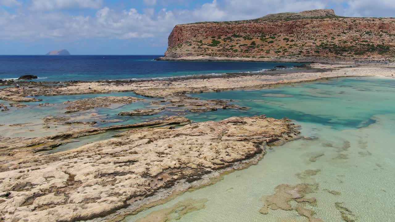 Balos Beach saltwater lagoon in Crete Greece with rocky formation division between it and the sea, Aerial pan right reveal shot