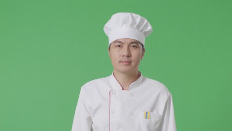 el chef asiático caminando en el estudio de fondo de la pantalla verde