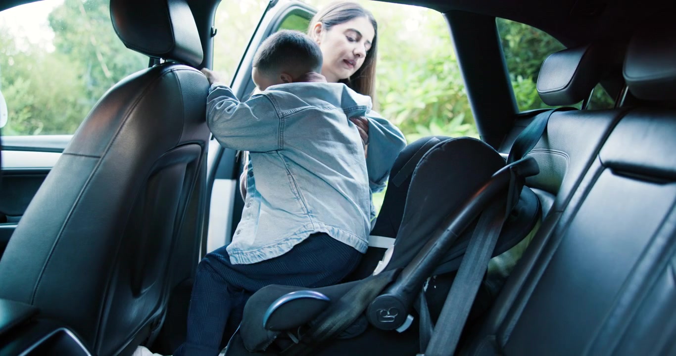 Madre ayudando a su hijo pequeño a salir del asiento del coche