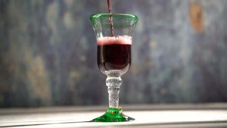clip de vino tinto en bucle sin costuras que se vierte en un vaso rústico con fondo azul