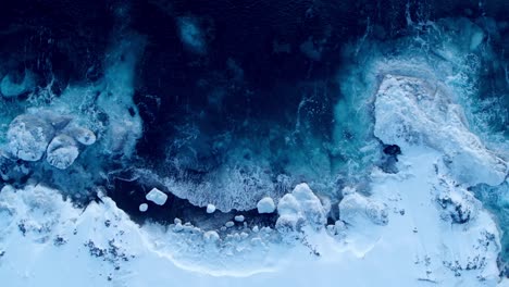 aerial view of waves crashing in the snowy environment