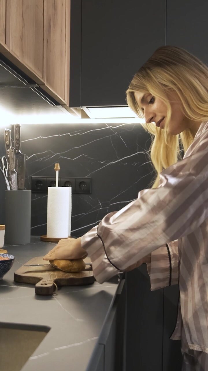 Giovane donna che affetta il pane in una cucina moderna