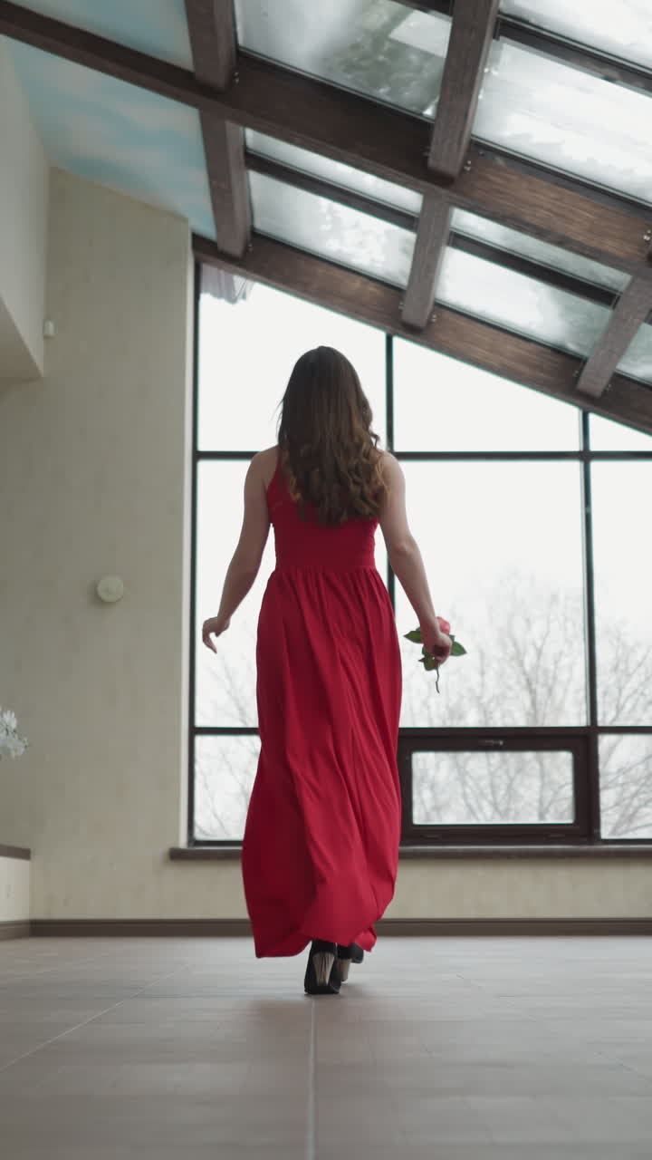 여성은 갤러리의 창문으로 달려갑니다. 여성의 손에 있는 장미는 미술 갤러리에서 은 옷의 움직임에 색의 폭발을 추가합니다. 역동적인 아름다움의 상징입니다.