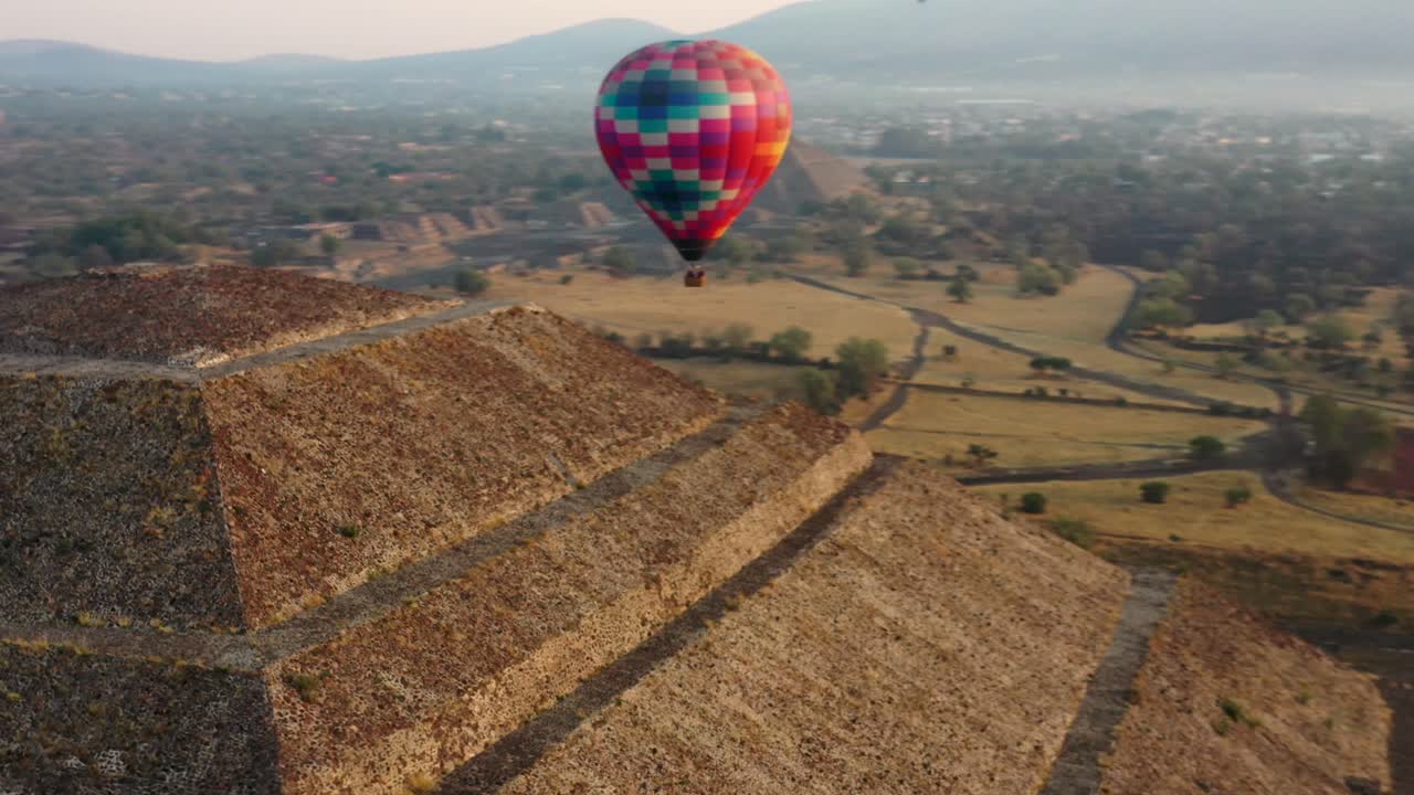 일출 동안 테오티후칸 멕시코의 아즈텍 문화의 피라미드 위로 날아가는 다채로운 열기구의 공중 전망, 4k
