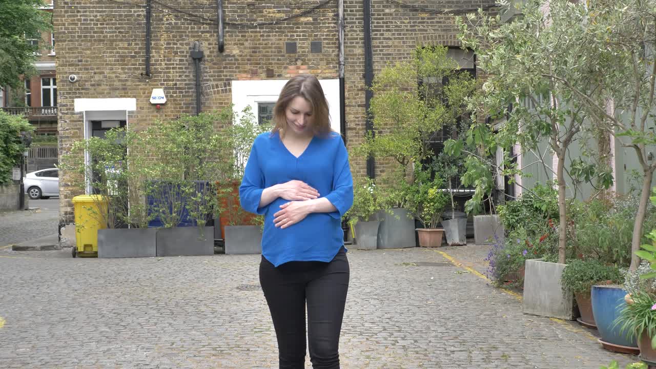 Pregnant caucasian woman walking down street in london