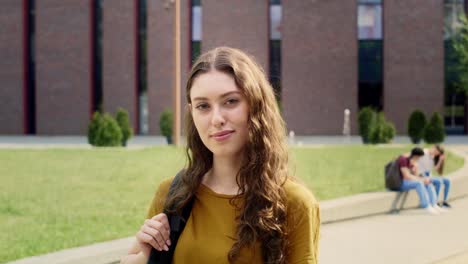 Portrait-of-female-university-student-standing-outside-the-university-campus