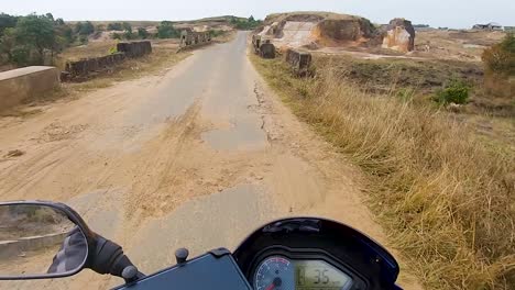 motociclista montando una bicicleta en un asfalto remoto durante el día desde un ángulo plano