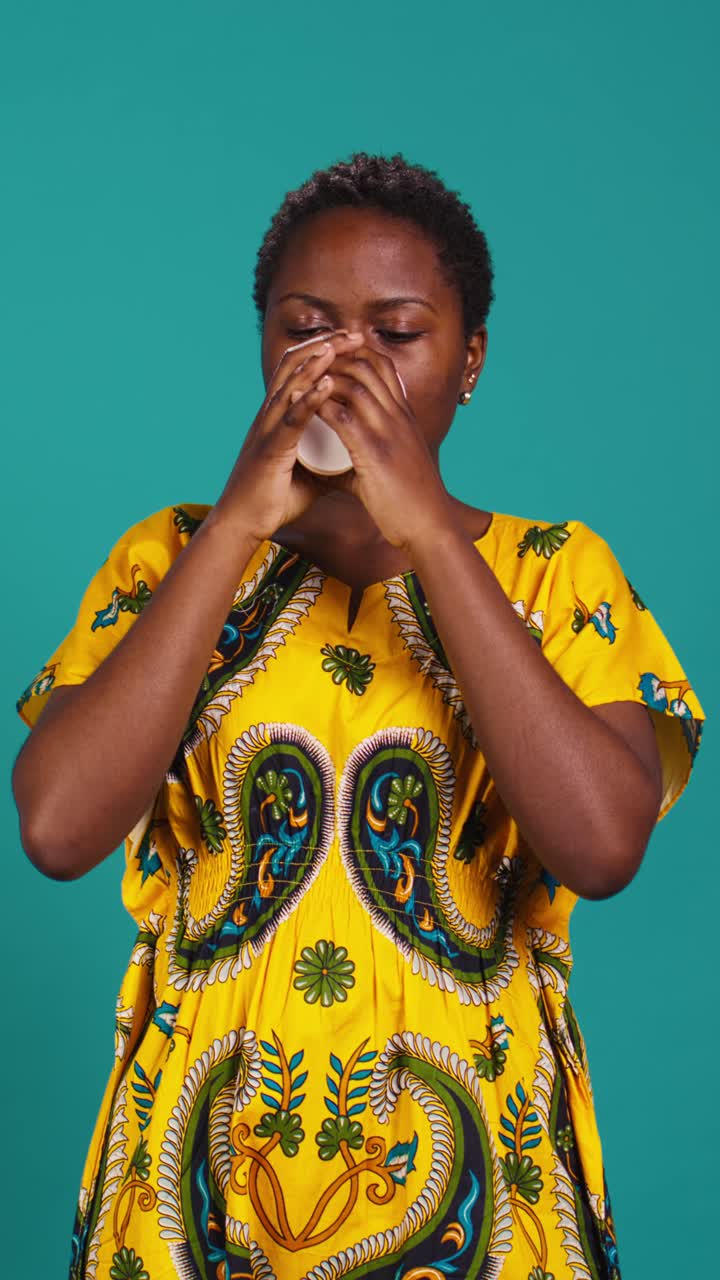 Donna africana che gusta una bevanda calda da una tazza