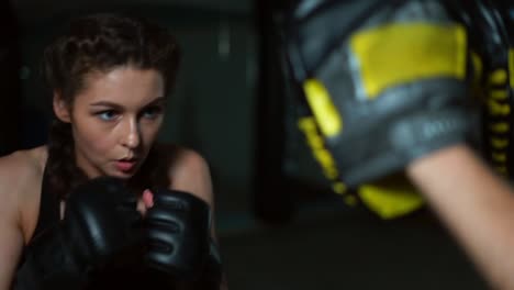 close up view of young attractive woman in boxing gloves training with her couch in a boxing club. slow motion shot