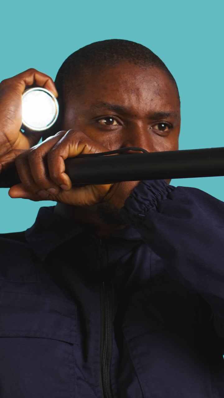 African Man Holding Flashlight and Baton Looking Alert