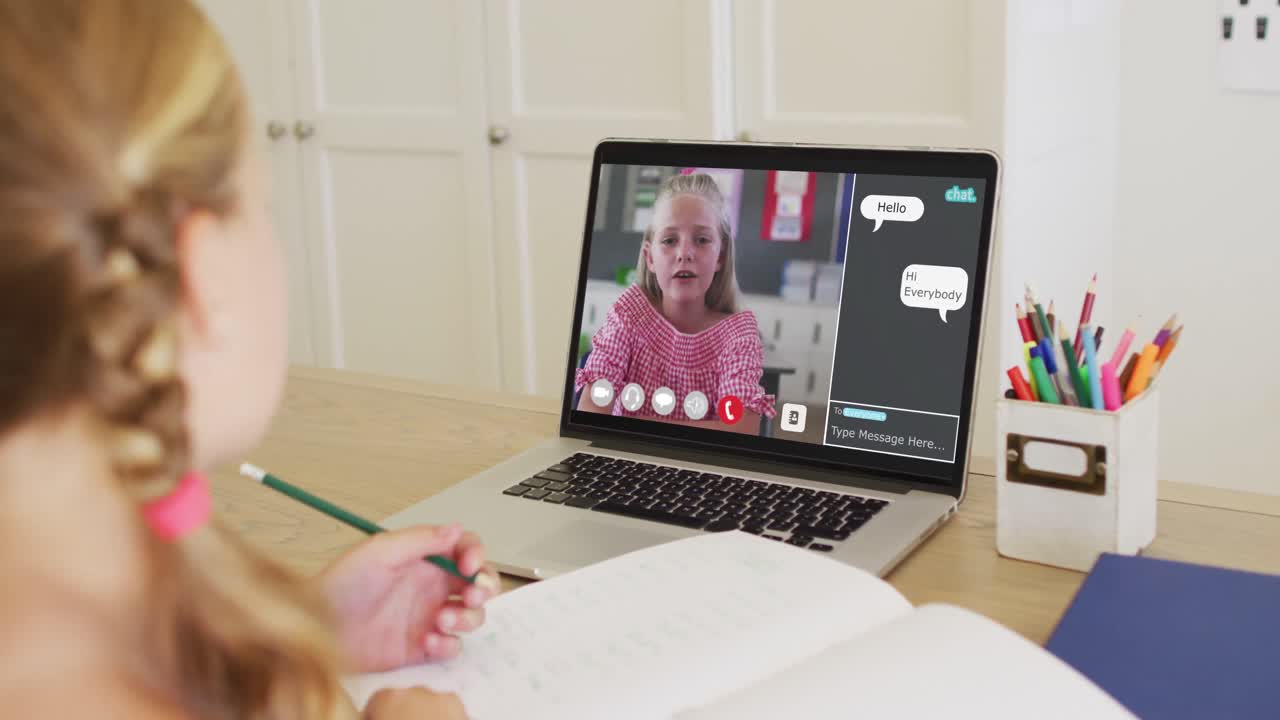 Schoolgirl using laptop for online lesson at home, with her colleague and web chat on screen