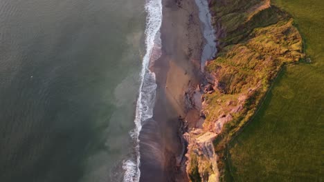 Drone-flying-along-the-sea-cliffs-at-Ballydwane-Copper-Coast-Waterford-Ireland-at-sunset-in-a-cold-winters-day