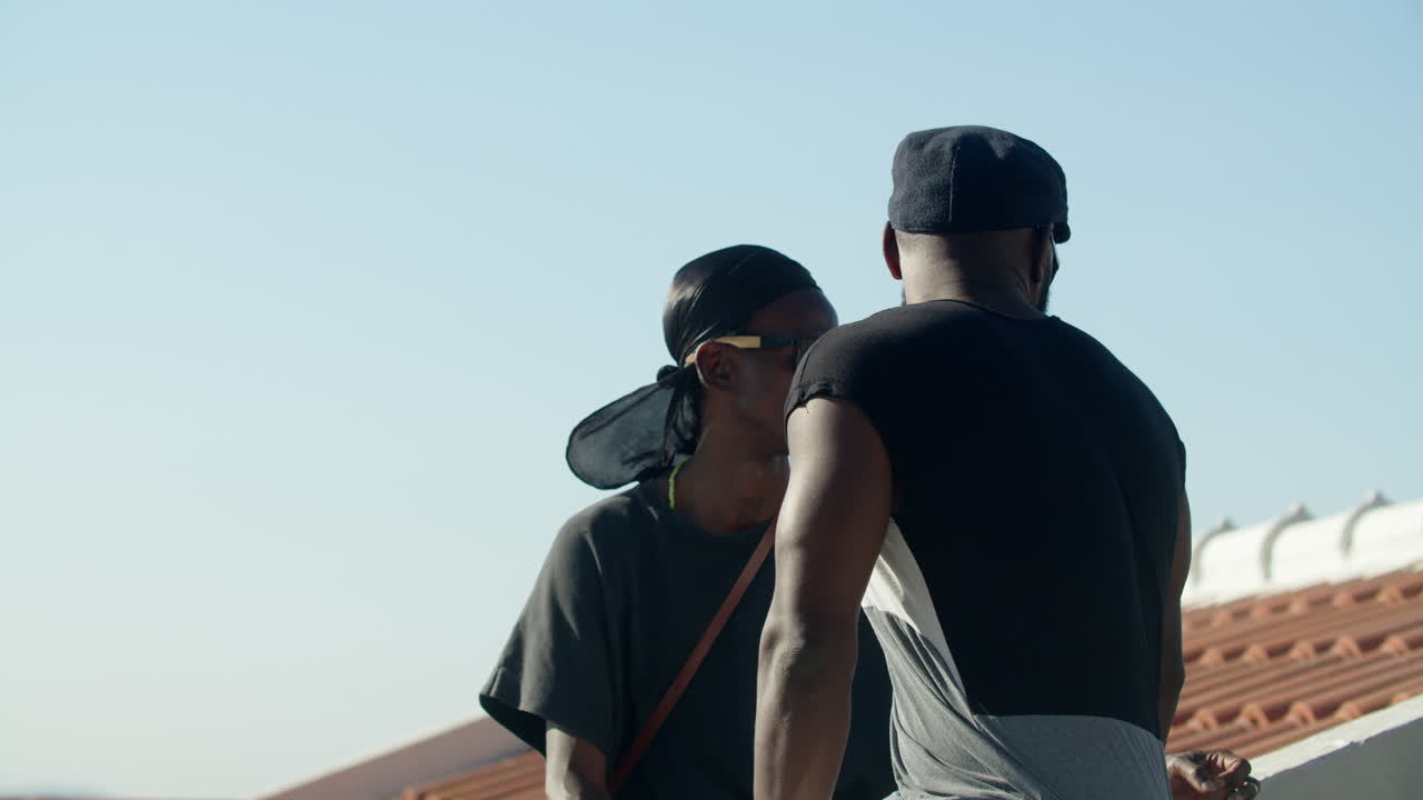 옥상에 앉아서 이야기하는 게이 커플의 중간 샷