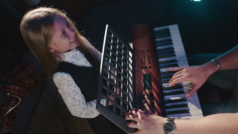 young girl learning to play the piano with her teacher