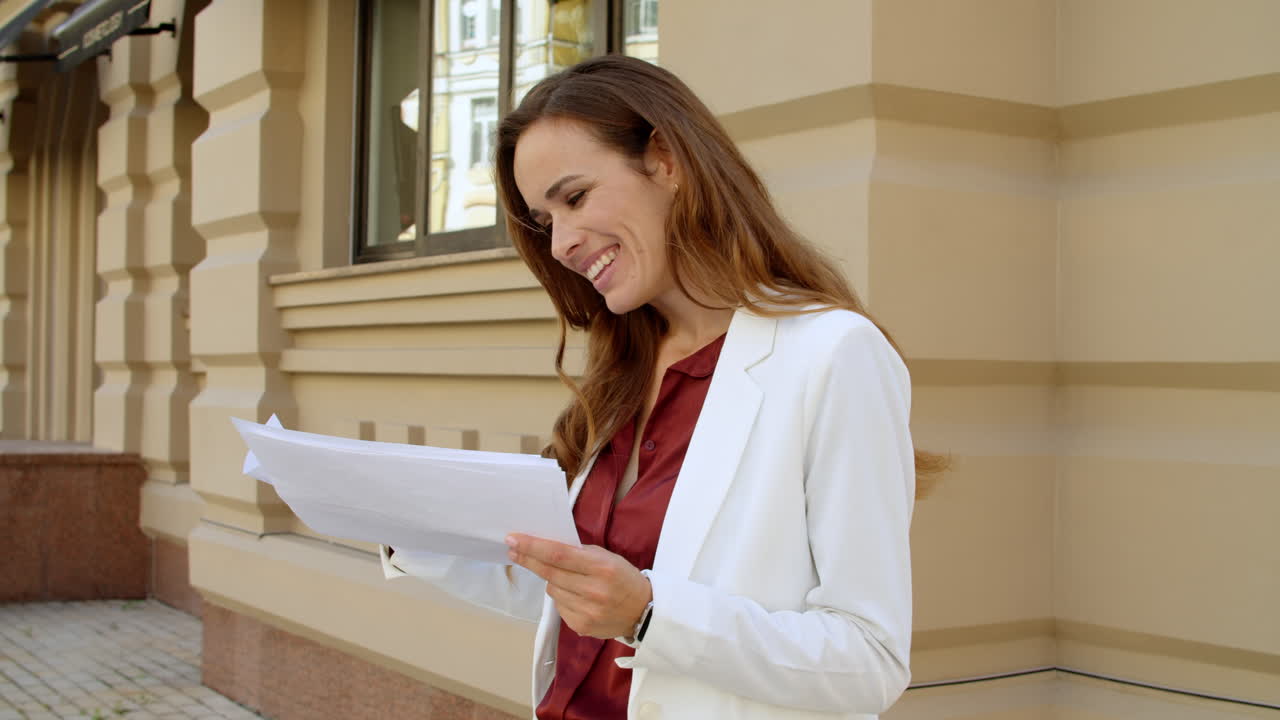 Excited woman reading documents outdoors
