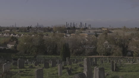 uk financial district looms on horizon with cemetery with gravestones in the foreground