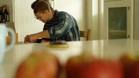 padre e hijo usando computadora portátil en la cocina 4k